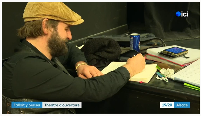 Jean-Michel concentré, prenant des notes dans un carnet en coulisses